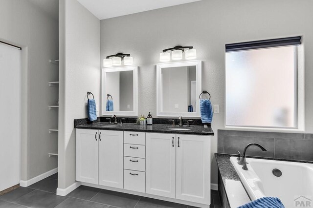 full bath featuring a bathtub, tile patterned flooring, a sink, and double vanity