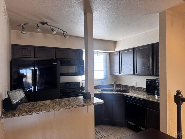 kitchen with a textured ceiling, black appliances, a sink, and light stone countertops