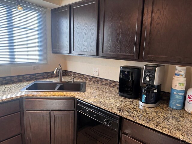 kitchen featuring dishwasher, light stone counters, a sink, and dark brown cabinetry