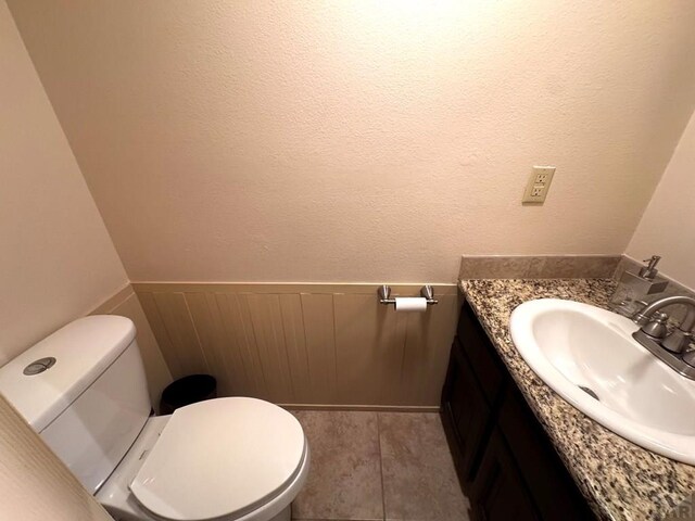 bathroom featuring toilet, vanity, and wainscoting