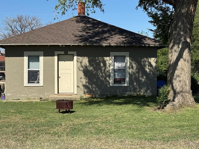 118 S 1st St, Cheraw, CO 81030 - rear view of property featuring roof with shingles, stucco siding, a yard, and a chimney