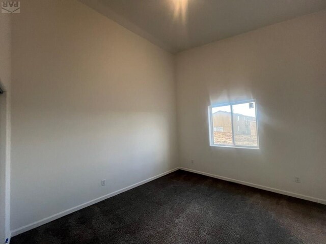 unfurnished room with dark carpet and baseboards