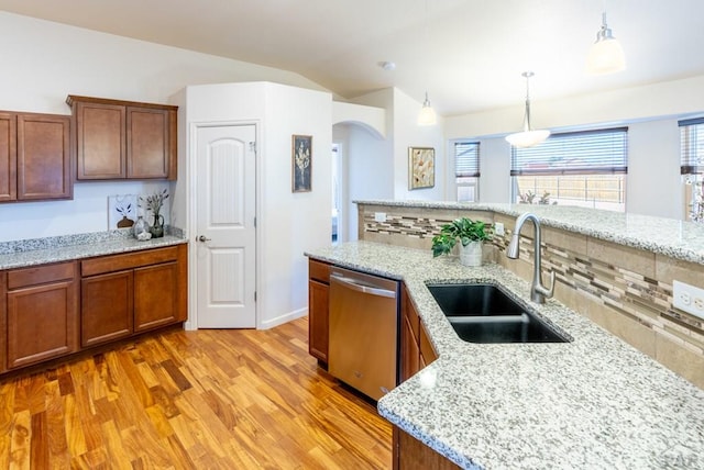 kitchen with vaulted ceiling, a sink, light wood-style floors, dishwasher, and arched walkways