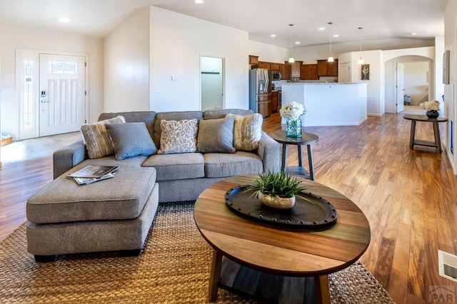 living area with recessed lighting, arched walkways, and light wood-style flooring