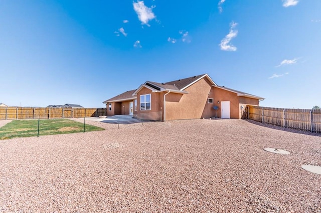 rear view of property featuring a patio, a fenced backyard, and stucco siding