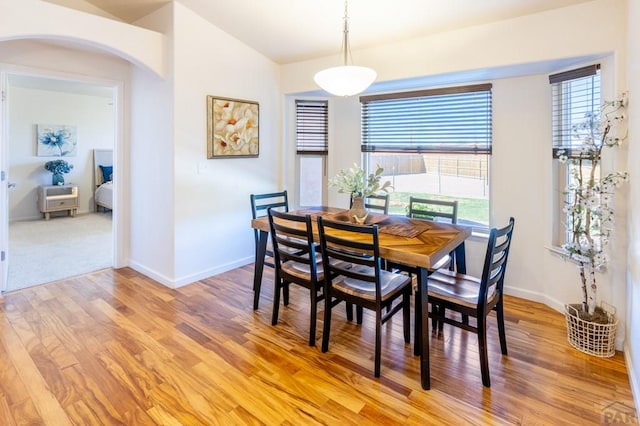 dining area featuring arched walkways, light wood-type flooring, a healthy amount of sunlight, and baseboards