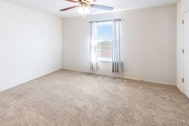 unfurnished room with carpet floors, visible vents, a ceiling fan, and baseboards