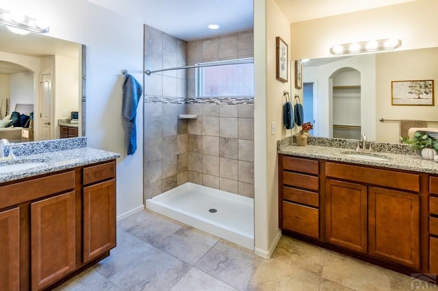 full bathroom featuring two vanities, baseboards, a sink, and a shower stall