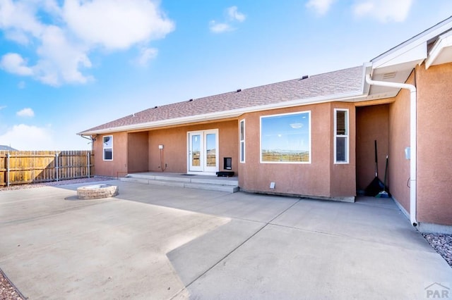rear view of house with french doors, a fire pit, fence, a patio, and stucco siding