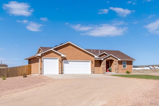 view of front of house with driveway, stone siding, fence, an attached garage, and stucco siding