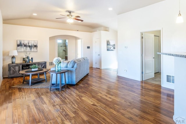living area with a ceiling fan, wood finished floors, arched walkways, lofted ceiling, and visible vents