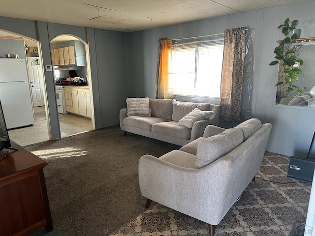 living area with arched walkways and light colored carpet