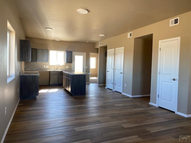 kitchen with a sink, dark wood finished floors, visible vents, and baseboards