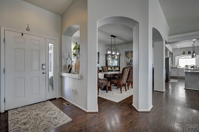 10919 Cascading Spring Cir, Peyton, CO 80831 - foyer entrance featuring baseboards, dark wood-style flooring, and arched walkways