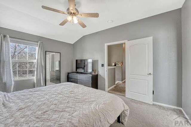 bedroom with a ceiling fan, lofted ceiling, light carpet, and baseboards