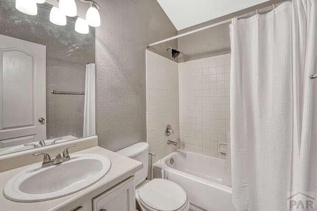 full bathroom featuring toilet, shower / bathtub combination with curtain, vanity, and a textured wall