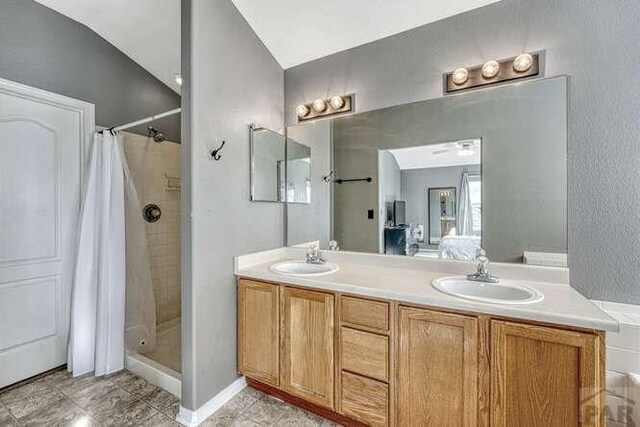 full bath featuring a sink, double vanity, a stall shower, and connected bathroom