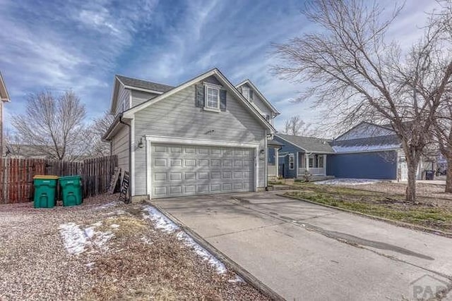 traditional-style house with a garage, driveway, and fence