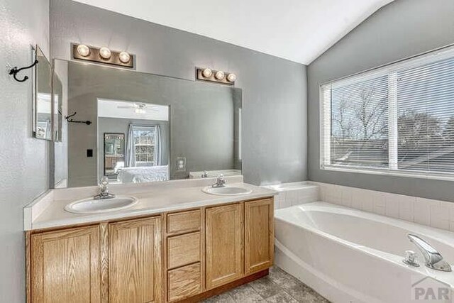 full bathroom with lofted ceiling, double vanity, a sink, and a bath