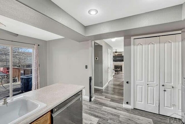 kitchen with dishwasher, light countertops, a sink, and light wood-style flooring