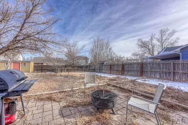 view of patio / terrace featuring an outbuilding, grilling area, a storage shed, an outdoor fire pit, and a fenced backyard