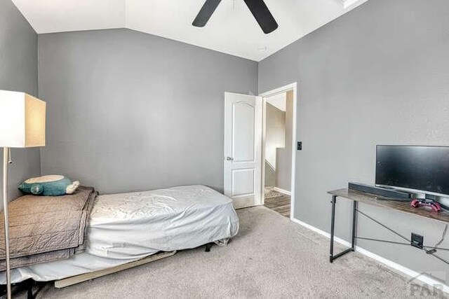 carpeted bedroom featuring a ceiling fan, lofted ceiling, and baseboards