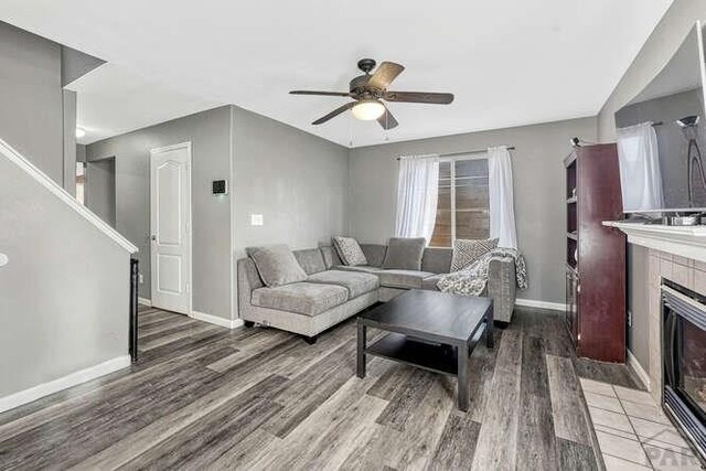 living room featuring a fireplace, wood finished floors, a ceiling fan, and baseboards