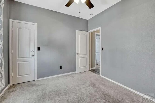 empty room featuring baseboards, a ceiling fan, and light colored carpet