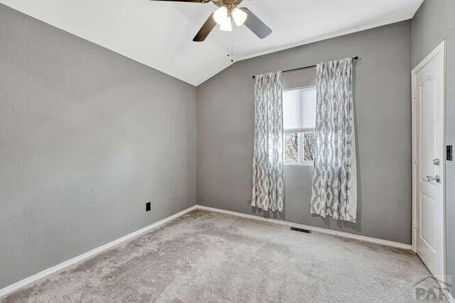 spare room featuring lofted ceiling, light carpet, and baseboards