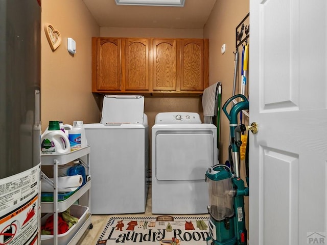 laundry room featuring water heater, washing machine and dryer, and cabinet space