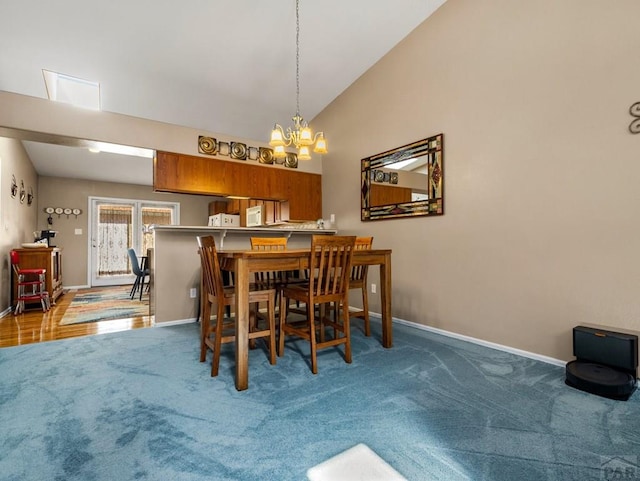 carpeted dining room with a notable chandelier, high vaulted ceiling, and baseboards