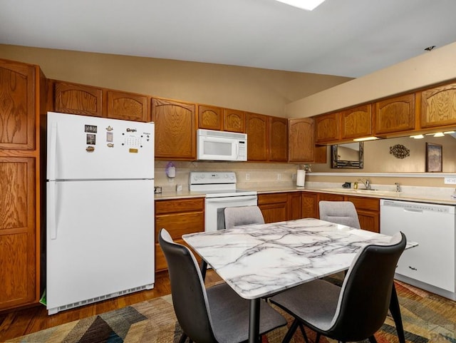 kitchen featuring vaulted ceiling, light countertops, white appliances, and brown cabinets