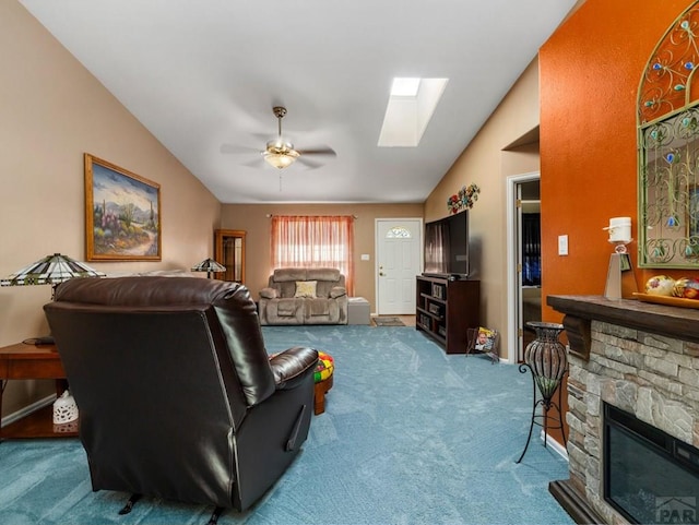 living room featuring vaulted ceiling with skylight, baseboards, a ceiling fan, carpet flooring, and a fireplace