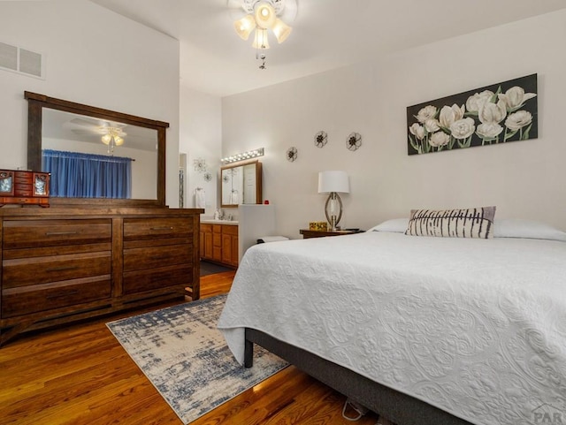 bedroom with a sink, connected bathroom, visible vents, and wood finished floors