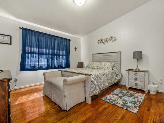 bedroom featuring baseboards, vaulted ceiling, and wood finished floors