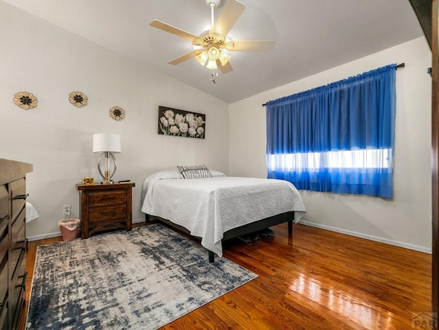 bedroom featuring a ceiling fan, vaulted ceiling, baseboards, and wood finished floors