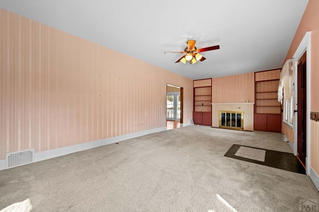 unfurnished living room featuring visible vents, carpet flooring, a brick fireplace, and ceiling fan