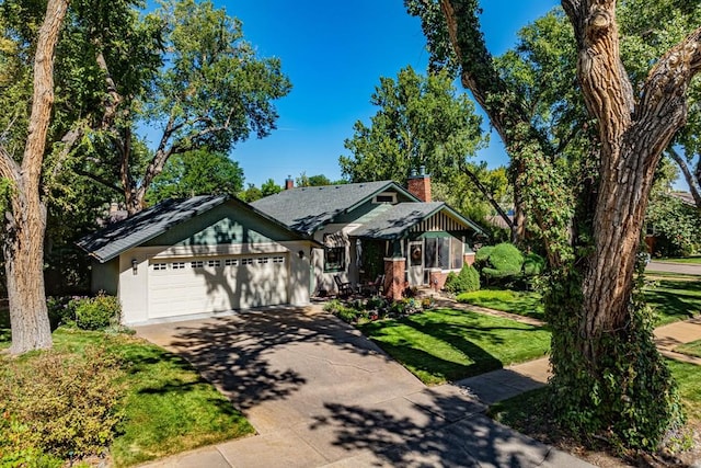 view of front of house featuring a chimney, an attached garage, concrete driveway, and a front lawn