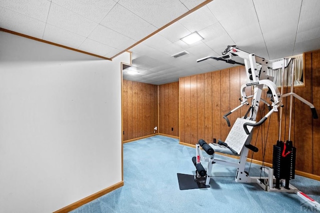 exercise area with visible vents, carpet floors, wooden walls, and baseboards