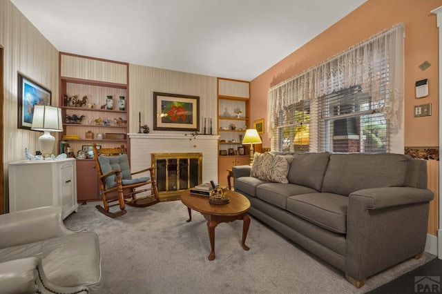 living area with a brick fireplace, built in shelves, and carpet floors