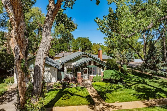 view of front facade featuring a chimney, a porch, and a front lawn