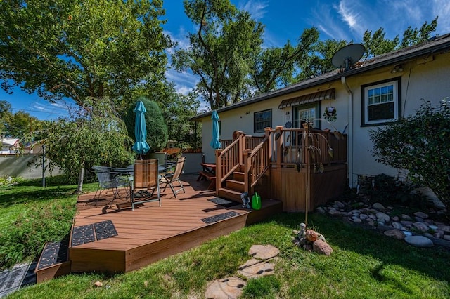 deck featuring outdoor dining space and a lawn