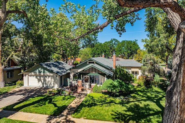 view of front of house featuring a garage, driveway, a chimney, and a front yard