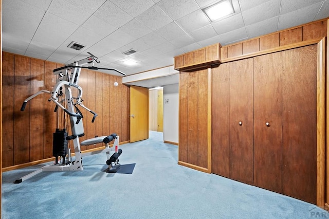 workout room featuring visible vents, baseboards, carpet, and wood walls