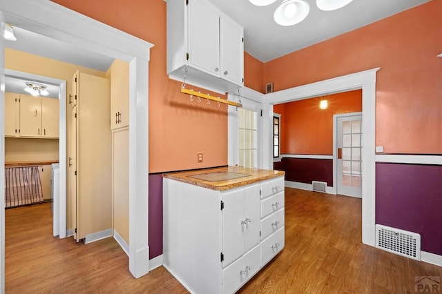 kitchen featuring light wood finished floors, visible vents, white cabinets, and baseboards