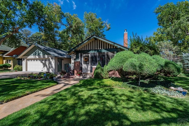 view of front of home with a chimney, concrete driveway, a garage, and a front yard