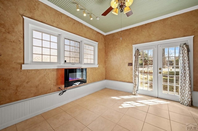 spare room with tile patterned flooring, a wainscoted wall, french doors, and a wealth of natural light