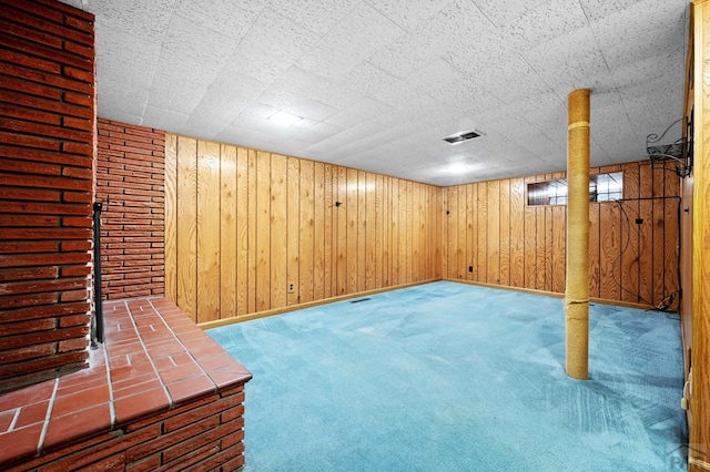 finished basement featuring carpet flooring, baseboards, and wooden walls