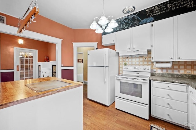 kitchen with under cabinet range hood, decorative backsplash, white appliances, and a chandelier