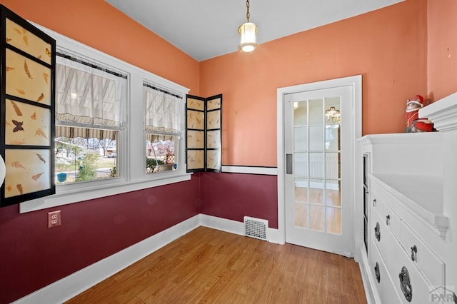 doorway with wood finished floors, visible vents, and baseboards